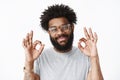 Close-up shot of kind and friendly adult african american bearded guy with pierced nose and afro hairstyle smiling