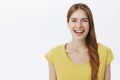 Close-up shot of kind happy charming european woman with braid in yellow birght t-shirt smiling joyfully at camera