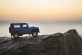 Close up shot of a Land Rover SUV vehicle on a rock and on sunset