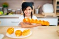 Close up shot little girl hold long bread and present to camera with smiling in kitchen in concept of happiness and enjoy to learn