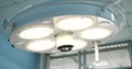 A close-up shot of a luminous surgical lamp in the operating room. A round lamp hangs over the table and shines brightly