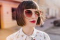 Close-up shot of magnificent european girl in white blouse. Outdoor photo of adorable woman in dark sunglasses..