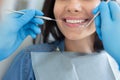 Close-up shot of male dentist examining teeth of young happy client