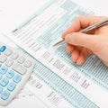 Close up shot of a male filling out US 1040 Tax Form with calculator next to it - close up studio shot Royalty Free Stock Photo