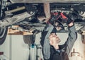 Mechanic Fixing Car Hoisted Up On Hydraulic Lift Royalty Free Stock Photo