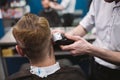 Close up shot of man getting trendy haircut at barber shop. Male hairstylist serving client, making haircut using machine and comb Royalty Free Stock Photo