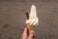 Close up shot of a hand holding whipped ice cream with a chocolate flake sticking out the side,  against a plain Royalty Free Stock Photo