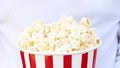 Close up shot of man people eating popcorn in striped bucket, focus on hands.