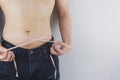 Close up shot of man with slim body measuring his waistline and torso. Healthy nutrition, diet and weight losing concept Royalty Free Stock Photo