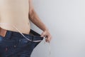 Close up shot of man with slim body measuring his waistline and torso. Healthy nutrition, diet and weight losing concept Royalty Free Stock Photo