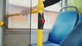 Close up shot man stands up to push red stop button on handrail in moving bus. Man presses pushbutton to make sign for