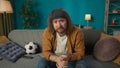 In the close up shot, a middle aged man is sitting on a sofa in the living room, against a blue wall, next to a ball. He Royalty Free Stock Photo