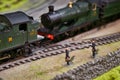 Close-up shot of miniature figures next to a model train track with detailed old-fashioned steam engine Royalty Free Stock Photo