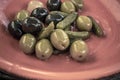 Close-up shot of mix of black and green olives with pickle in an orange bowl Royalty Free Stock Photo