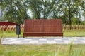 Close up shot of a modern brown wooden bench and a trash bin surrounded by grass on in the park of the Serdtse Stolitsy Royalty Free Stock Photo