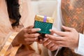 Close up shot of muslim woman hand receiving gift box from husband during Ramzan fest celebration at home.