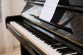 Close-up shot of old piano with open keyboard and paper sheet with notes Royalty Free Stock Photo