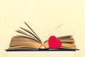 Close-up shot of open old book with red heart by side Royalty Free Stock Photo