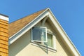 Close up shot with open window in attic of white stucco house with chimney with orange slatted wood with double gable Royalty Free Stock Photo