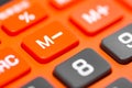 An orange calculator focuses on M- or subtract from memory button. Close up macro.