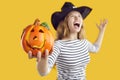 Close up shot of an orange Halloween pumpkin in the hand of a funny, crazy witch Royalty Free Stock Photo