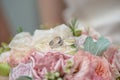 Close-up shot of pastel bridal bouquet of roses and silk with two wedding rings resting on a white rose, ready for the wedding