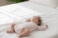 Close up shot peaceful babygirl in bodysuit sleeping on bed