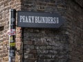 Close-up shot of the Peaky Blinders banner on a brick wall in London, UK