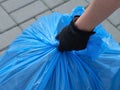 A closeup shot of a person hand taking a blue garbage bag full of trash Royalty Free Stock Photo