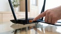 Person connecting an ethernet cable to a black wireless router on a glass table Royalty Free Stock Photo