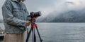 Close-up shot of a photo camera on a tripod and the hands of a woman photographer making settings for shooting on the Royalty Free Stock Photo