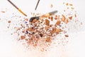 Close-up shot of pieces of cosmetic powder with makeup brushes falling Royalty Free Stock Photo