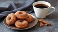 A close-up shot of a plate of cinnamon sugar donuts next to a cup of coffee and several cinnamon sticks Royalty Free Stock Photo