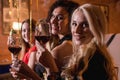 Close-up shot of positive beautiful female friends raising glasses of wine to happy event sitting in fashionable