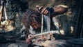 Close-up Shot of a Primeval Caveman Wearing Animal Skin Trying to make Fire with Bow Drill Method. Royalty Free Stock Photo