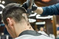 Close up shot of professional barber working with hair clipper, making trendy haircut for client. Man visiting Royalty Free Stock Photo