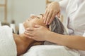 Close up shot of a professional masseuse doing a facial and head massage for her female client.