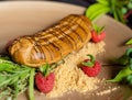Close-up shot of a raspberry eclair served with crushed biscuits leaves and chocolate ganache Royalty Free Stock Photo