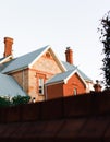 Close-up shot of a red brick Colonial home during dusk behind tall fence or wall Royalty Free Stock Photo