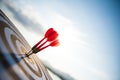 Close up shot red darts arrows in the target center on dark blue sky background. Business target or goal success and winner Royalty Free Stock Photo