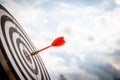 Close up shot red darts arrows in the target of dartboard center on dark blue sky background. Business target or goal success and Royalty Free Stock Photo