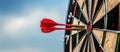 Close up shot red darts arrows in the target of dartboard center on dark blue sky background. Business target or goal Royalty Free Stock Photo