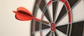 Close up shot red darts arrows in the target of dartboard center on dark blue sky background. Business target or goal Royalty Free Stock Photo