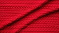 Close up of a red knitted fabric with a braid pattern and a slight fold creating a shadow effect Royalty Free Stock Photo