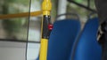 Close up shot of red stop button on handrail pushed by man in moving bus. Man presses pushbutton to make sign for driver