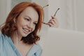 Close up shot of redhead businesswoman makes video call to business partner, has discussion with corporate partner, holds optical Royalty Free Stock Photo