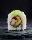 Close-up shot of a roll of sushi on a black stone plate Royalty Free Stock Photo