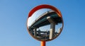 Convex Traffic Mirror Reflecting an Elevated Highway Bridge and City Buildings Against a Blue Sky Royalty Free Stock Photo