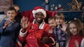 Close up shot of santa claus and cute kids waving to the camera.