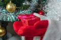 Close up shot of Santa Claus holding a red gift box in both hands. Christmas tree with red and golden balls, white tinsel blurred Royalty Free Stock Photo